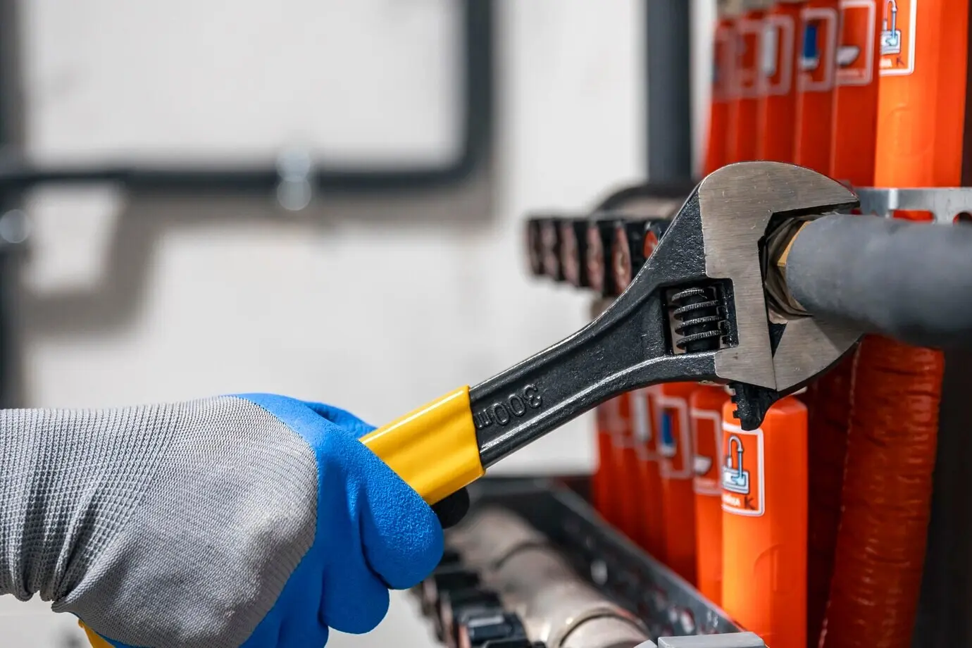 Hände, die mit einem Schraubenschlüssel Ventile zudrehen.